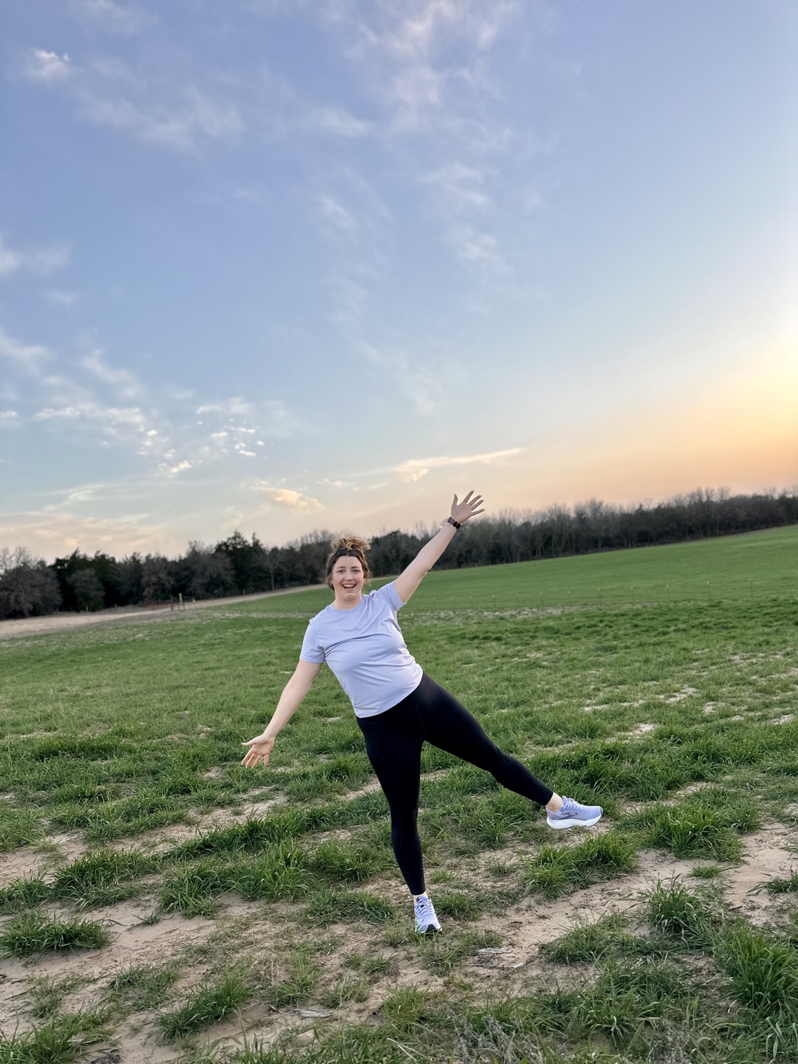 Rachel smiling playfully in a green Oklahoma field at sunset
