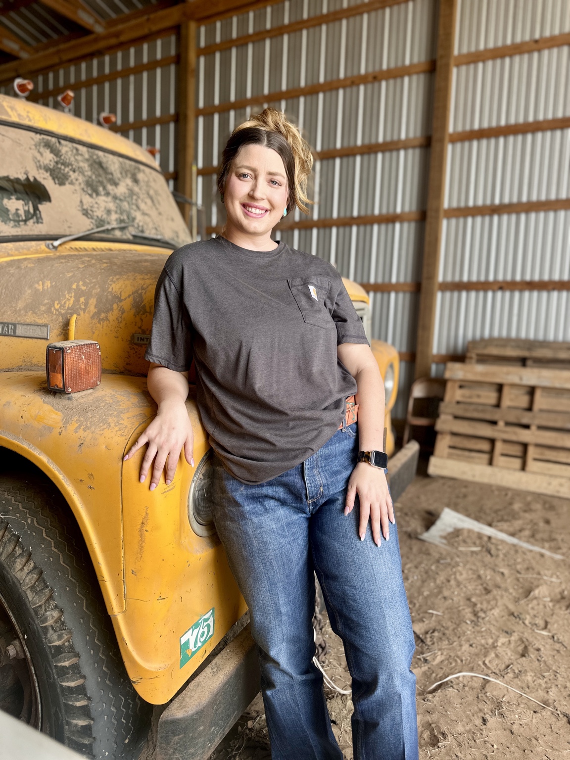 Rachel Buford Black smiling beside a vintage yellow farm truck